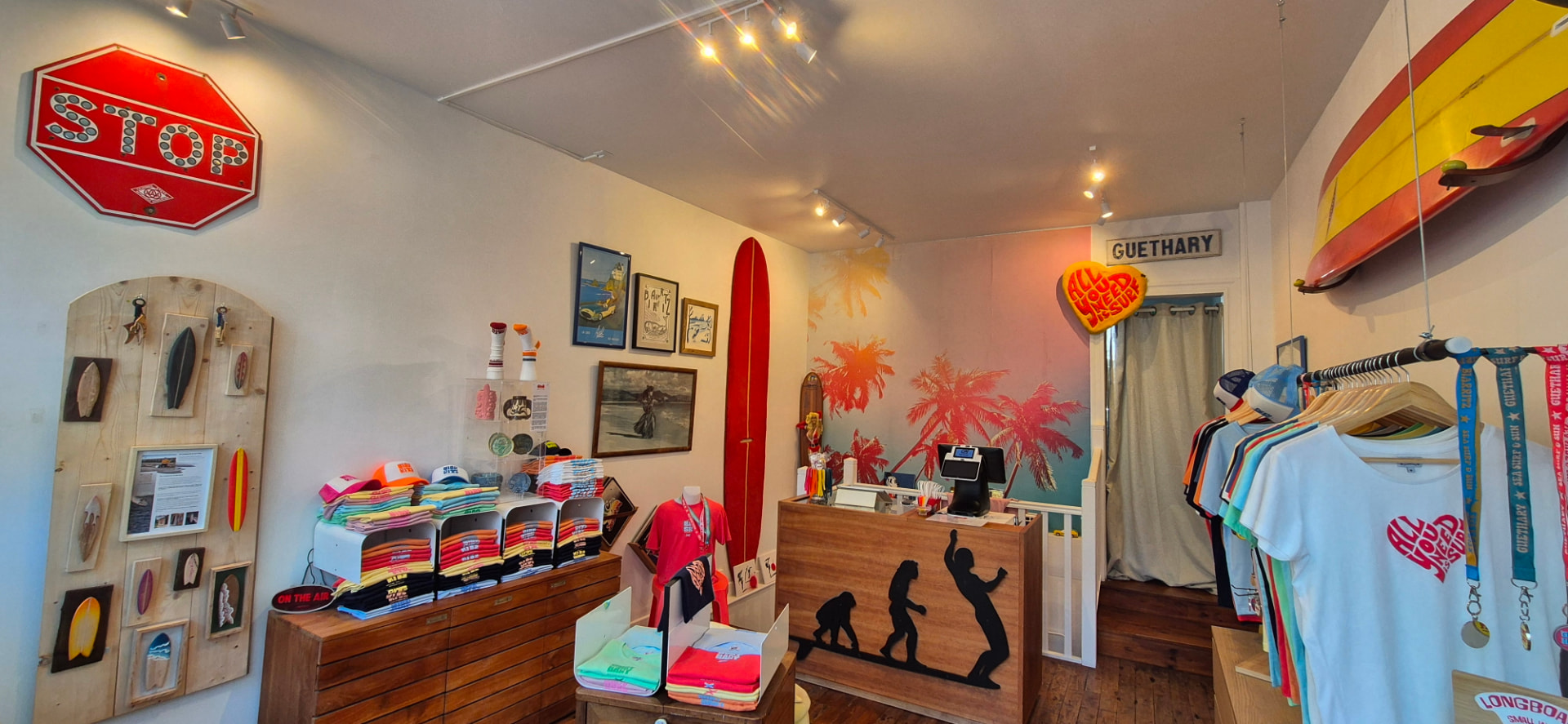 L'intérieur de la boutique Côte B à Biarritz : planches vintage, panneaux STOP et Guéthary, mur aux palmiers roses